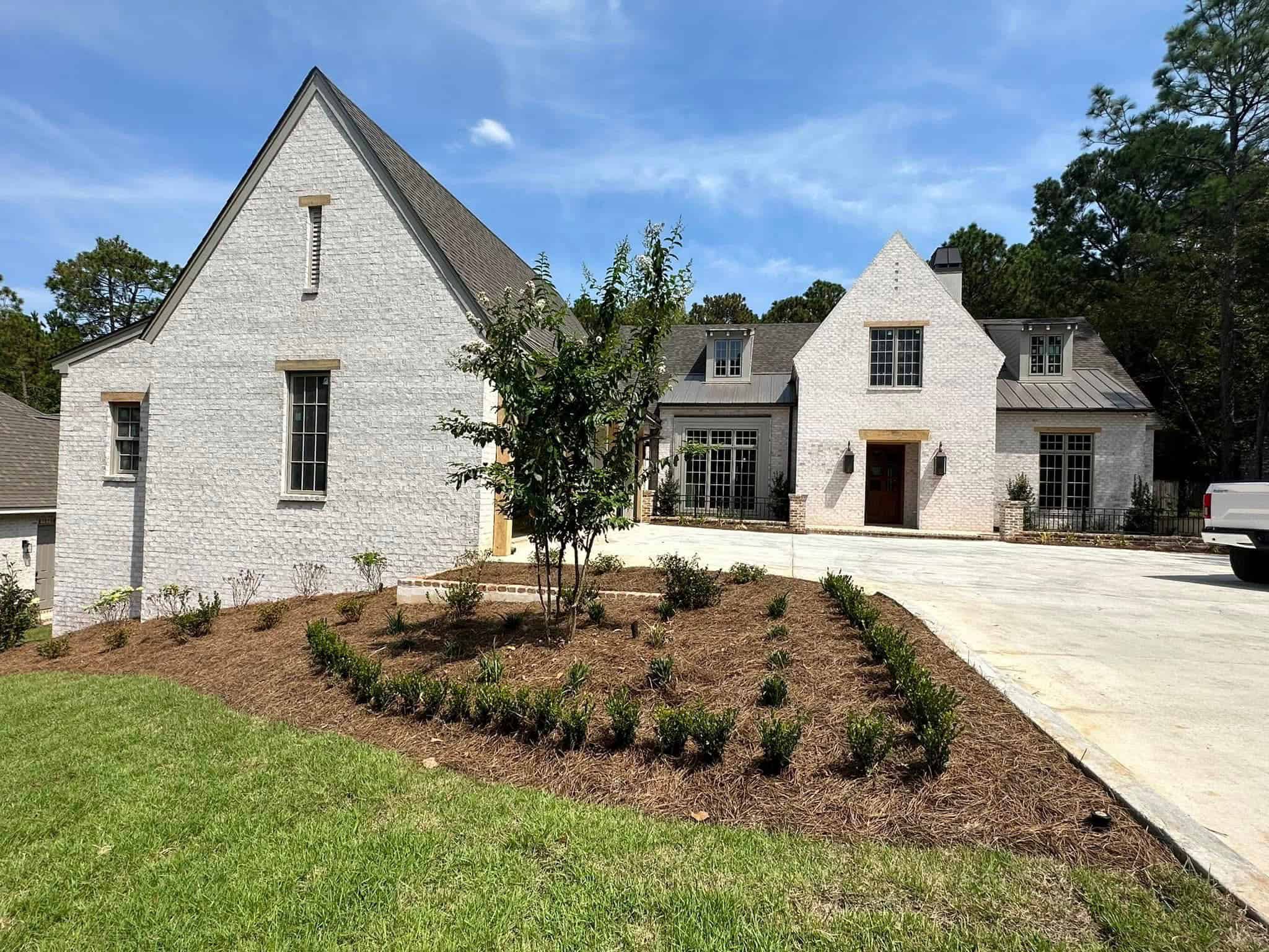 A large white new build house with a driveway and landscaping.